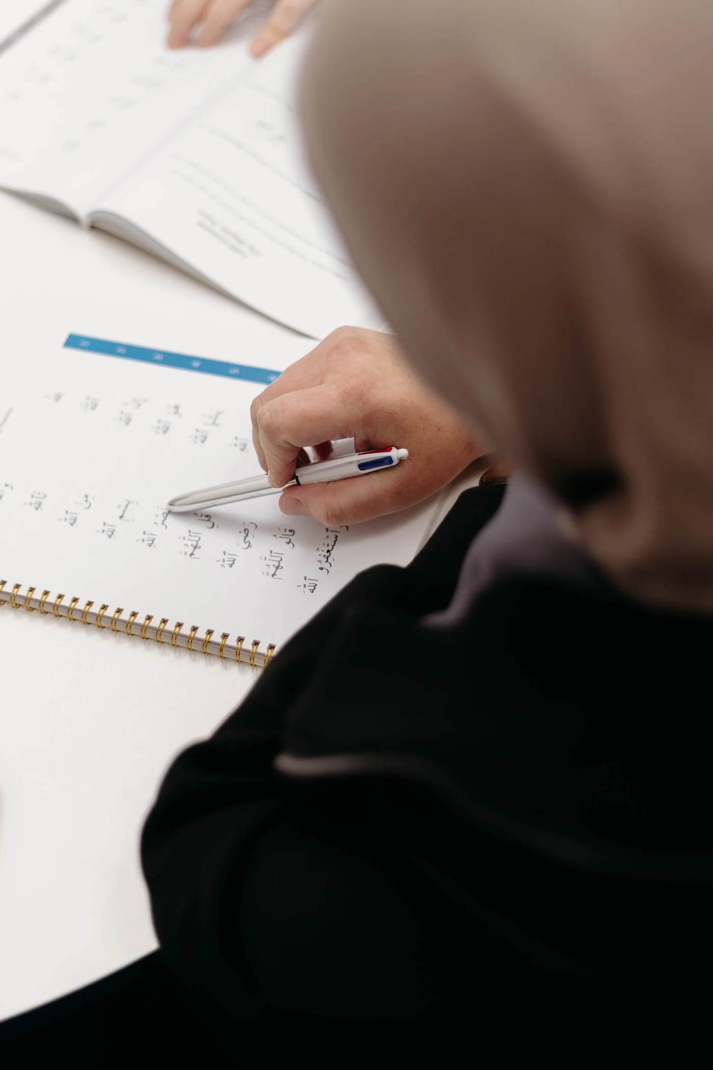 A student following Arabic reading notes with a pen